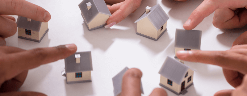 group of people touching miniature houses